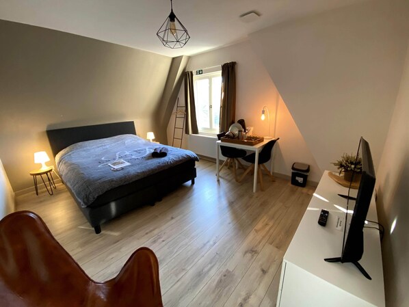 A bedroom with a bed, desk, chair, TV, and a window with curtains. - B&B De Hoogmolen (Bruges)