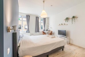 A modern bedroom with a bed, bedside table, TV, and a desk with a chair. - B&B De Hoogmolen (Bruges)