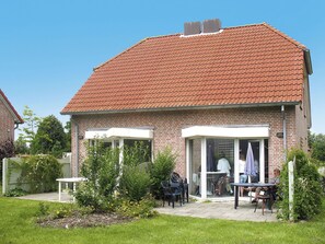 Guests can enjoy a patio with a table and chairs, surrounded by a lush garden.