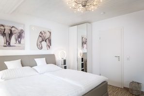 A bedroom with a large bed, white bedding, and two wall-mounted light fixtures.