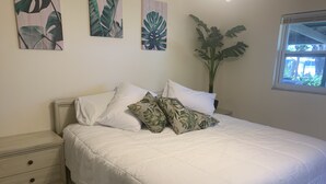A bedroom with a bed, white bedding, a nightstand with drawers, and three wall-mounted plant prints. - Waterfront home w/dock-Jon boat, Kayaks & fishing poles included! (Port Richey)