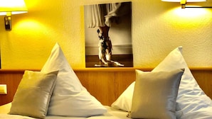 A hotel room with a bed, pillows, and two wall-mounted lamps. - Hotel Austria Stuttgart-City (Stuttgart)