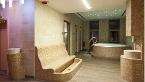 A modern spa area with a large bathtub, a seating area, and a small sink. - Golte Apartments (Mozirje)