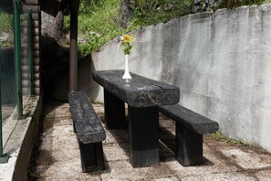 A concrete bench with a white vase of flowers. - Golte Apartments (Mozirje)