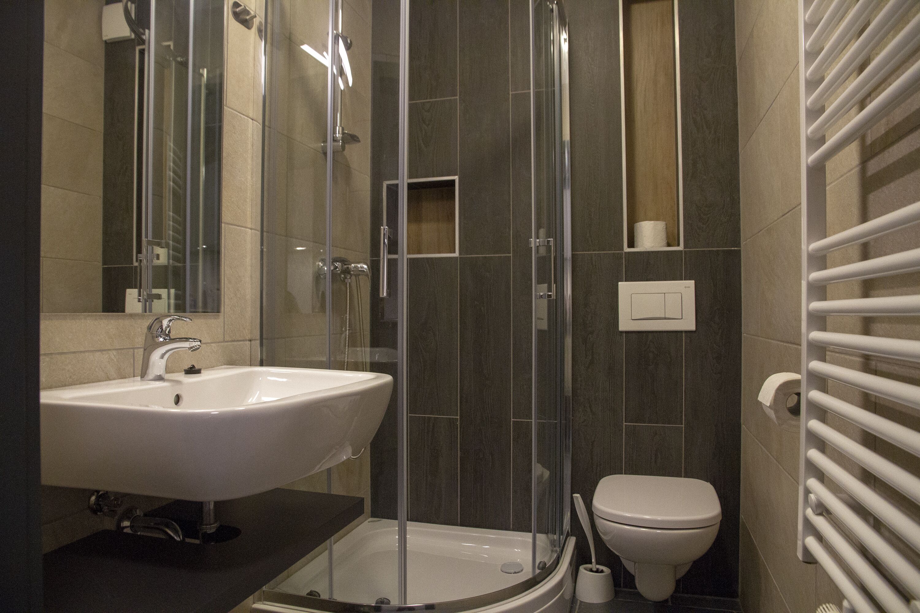 Un bagno moderno con doccia vetrata, lavandino bianco e water.