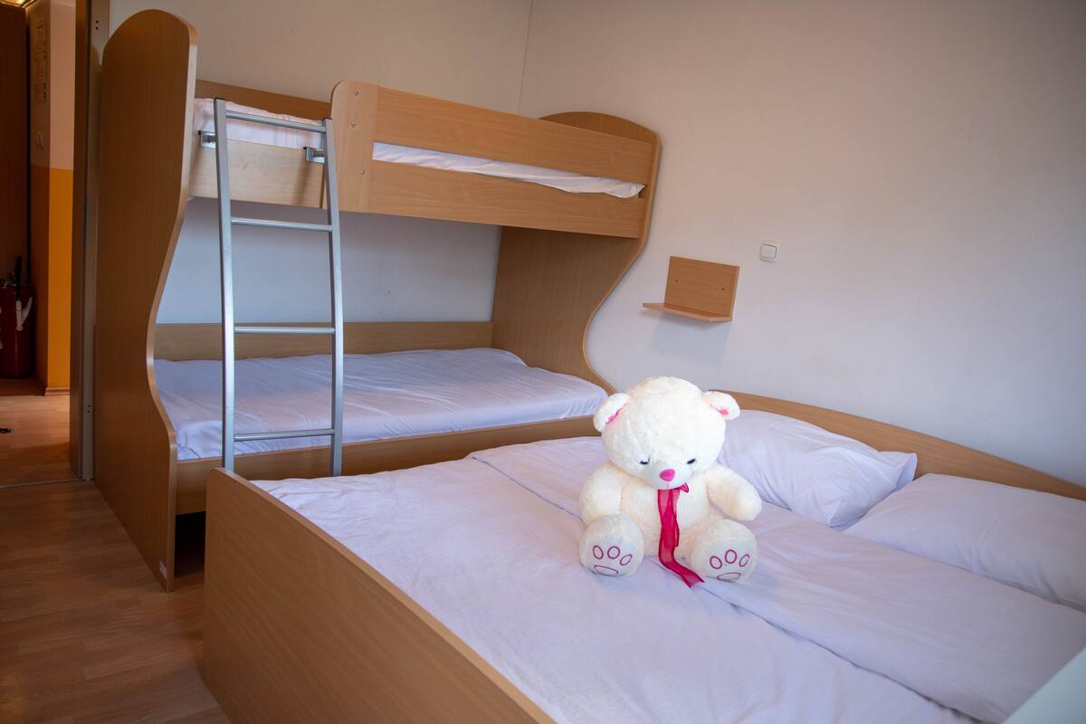 Une chambre avec un lit superposé, et un ours en peluche posé sur le lit du bas.