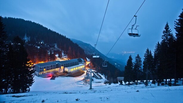 A ski resort with a building, ski lift, and snowy landscape. - Golte Apartments (Mozirje)