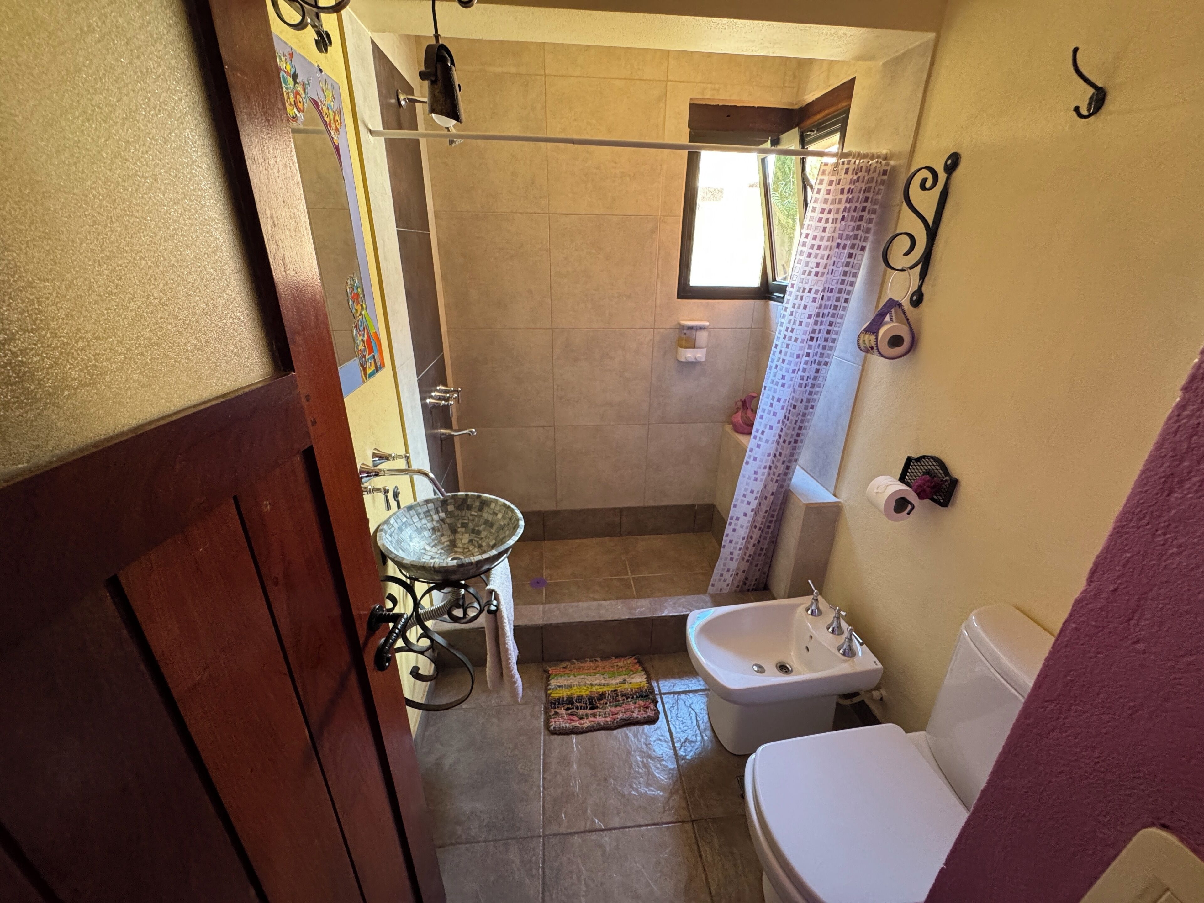 A bathroom with a toilet, bidet, sink, and shower area.