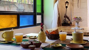 Een ontbijttafel gedekt met gele bekers en een rieten mand.