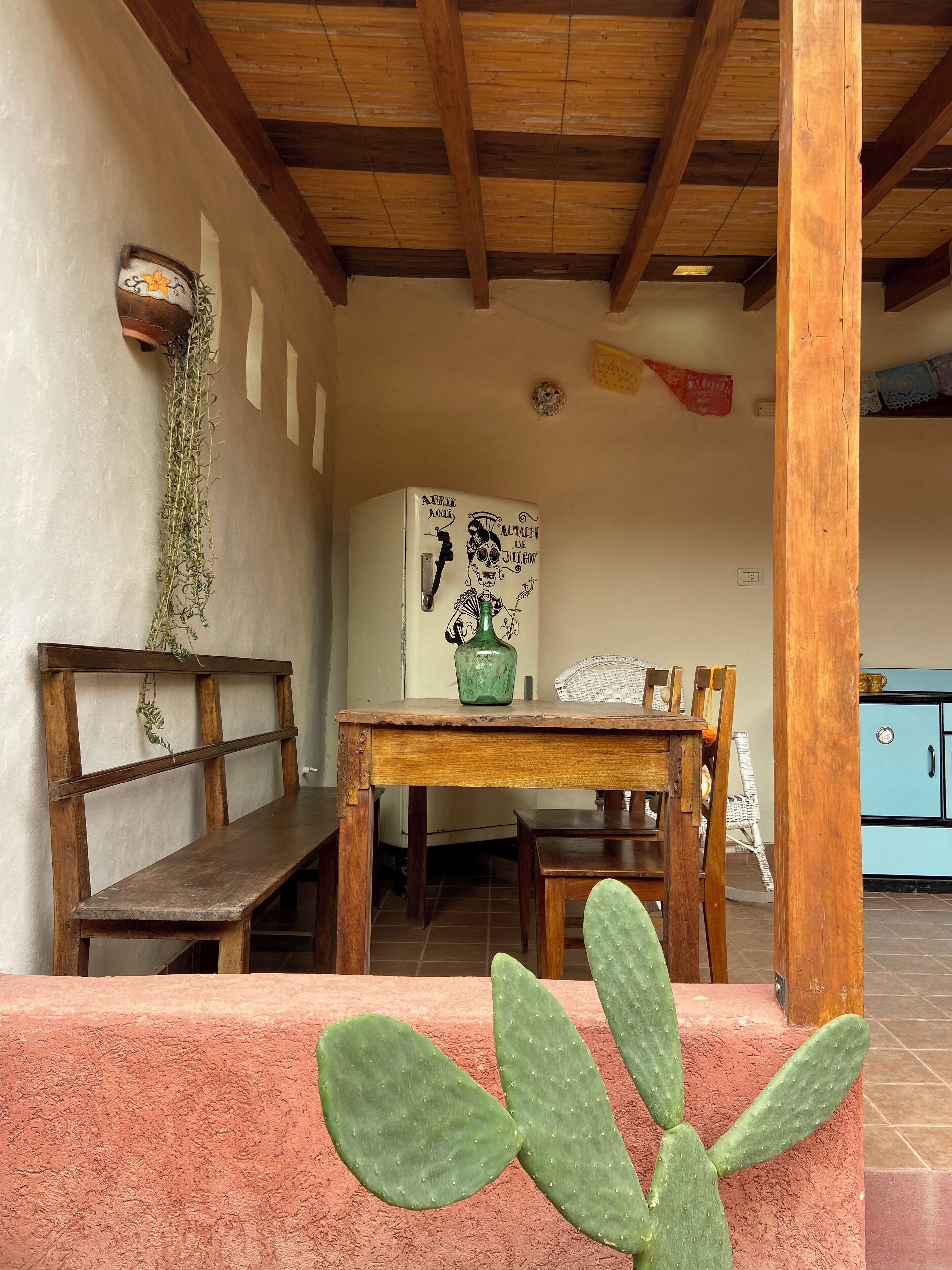 Een rustieke eethoek met een houten bank, een tafel en een cactus.