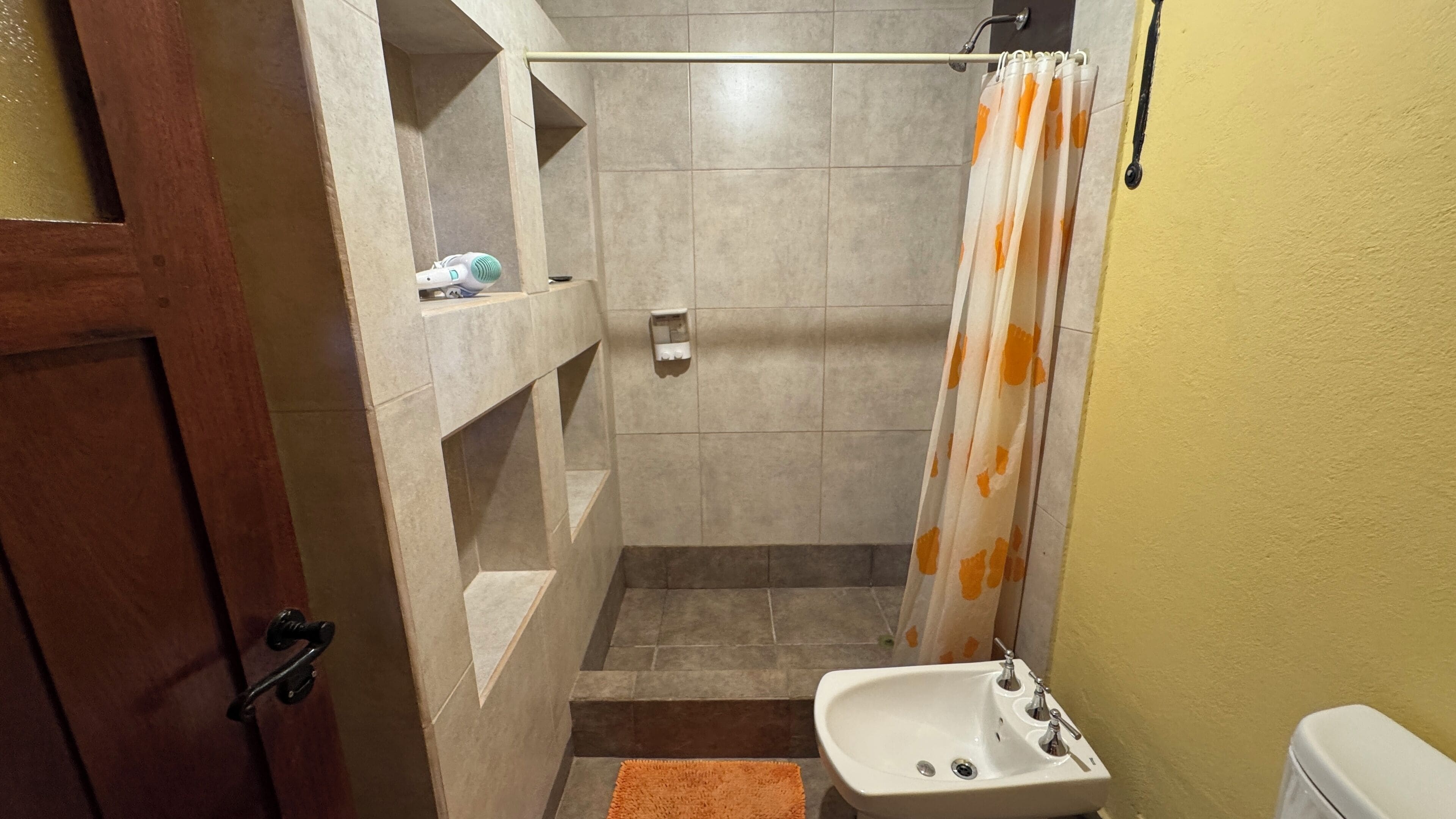 A bathroom with a shower, a sink, and a toilet.