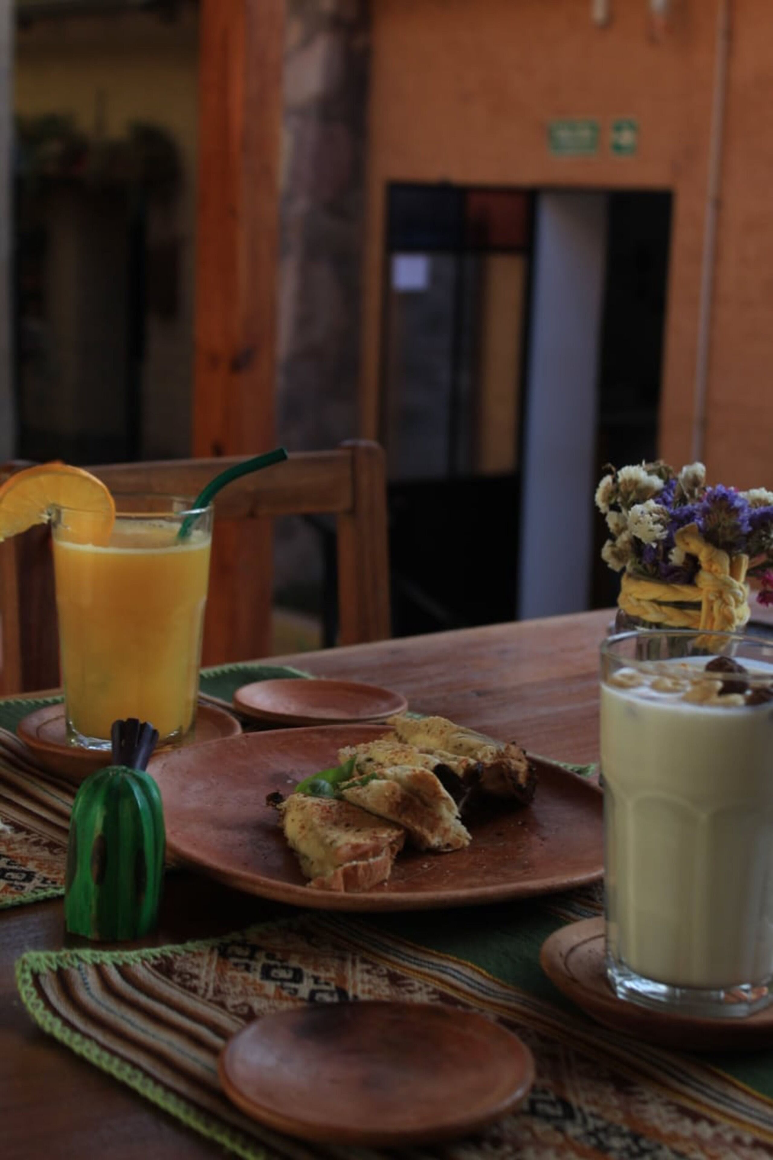 A table with a glass of orange juice, a sandwich, and a glass of milk.