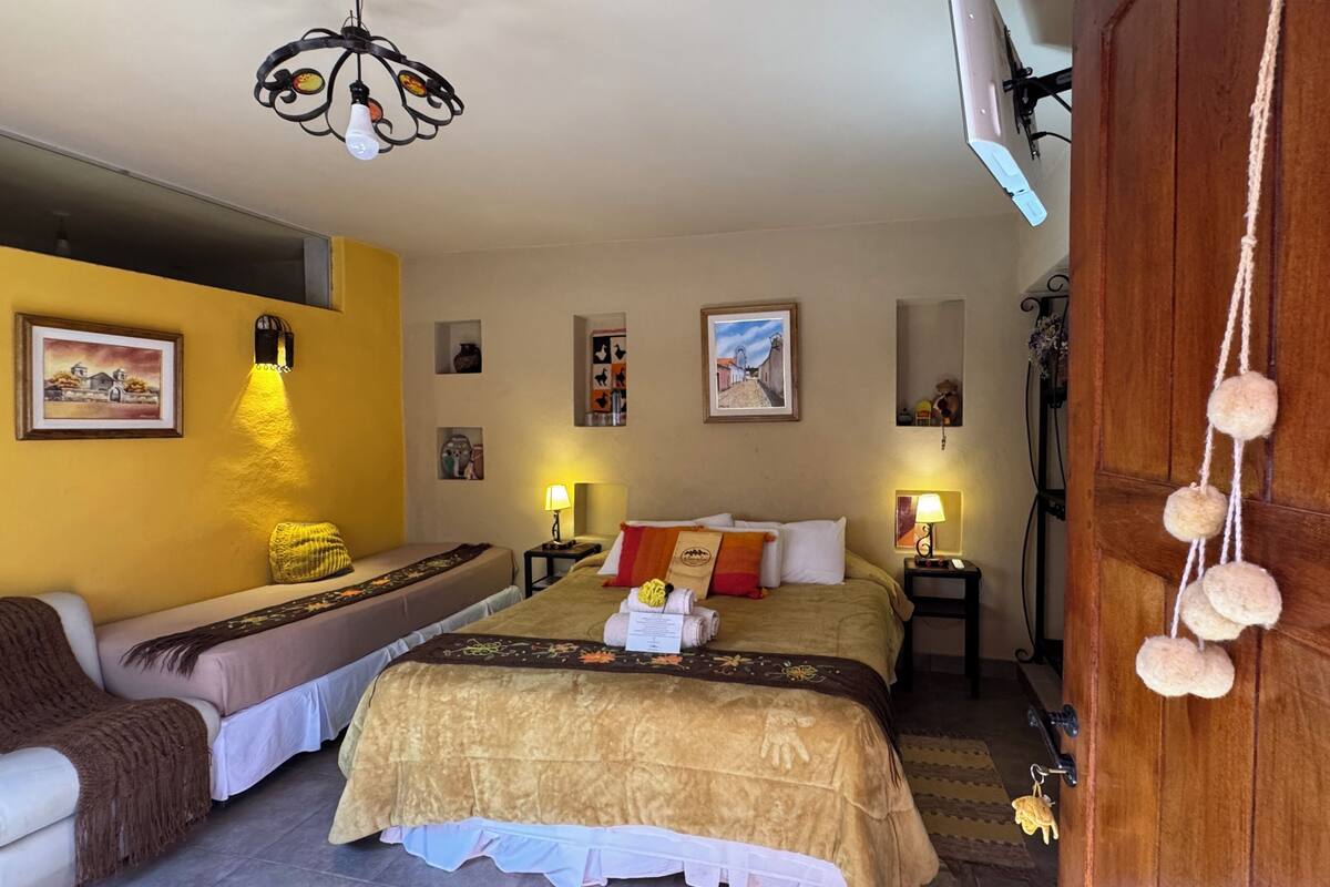 Une chambre d’hôtel avec un lit, un canapé, un bureau et une armoire en bois.