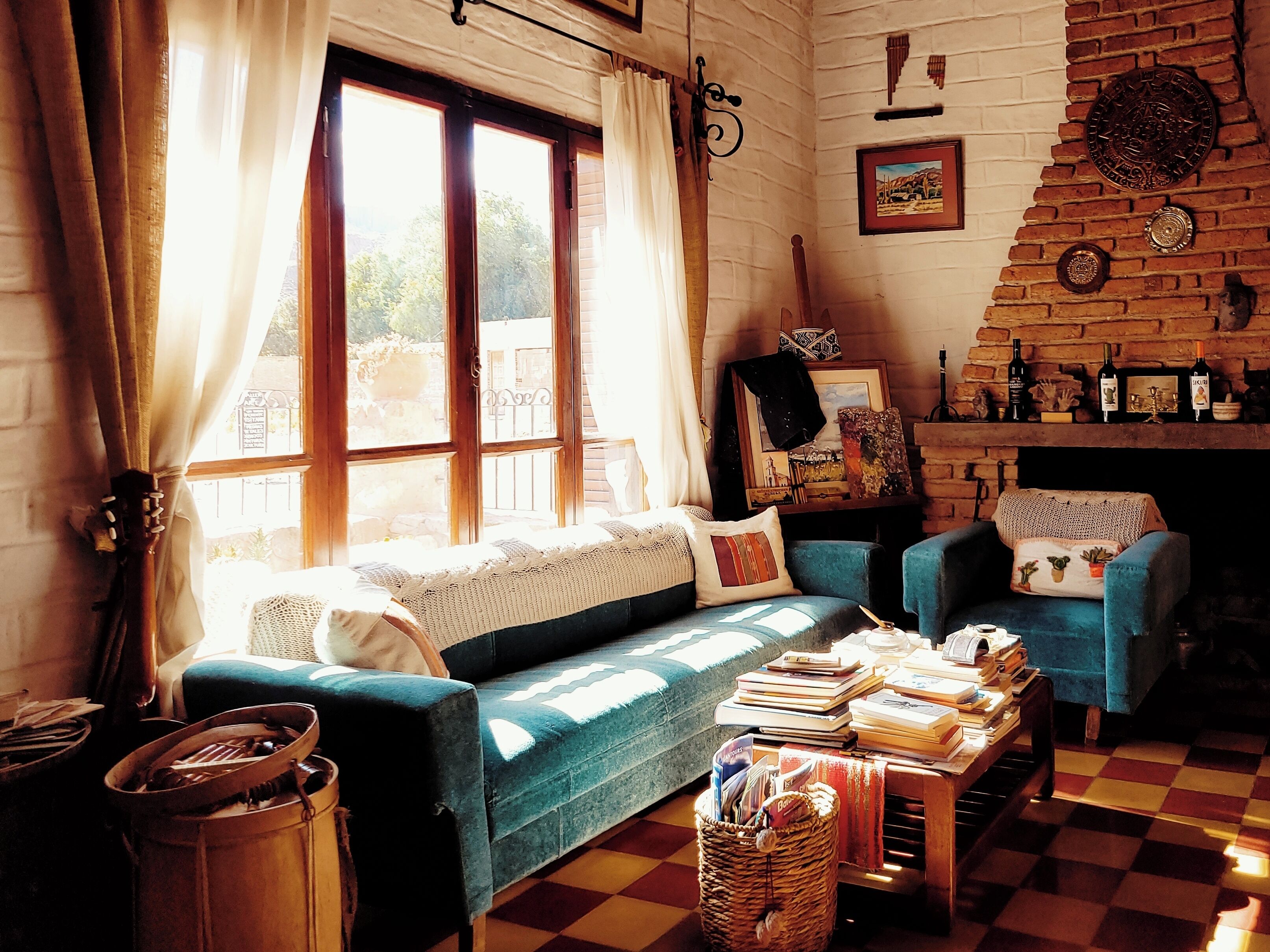 A cozy living room with a blue sofa, a wooden table with books, and a fireplace with decorative items.
