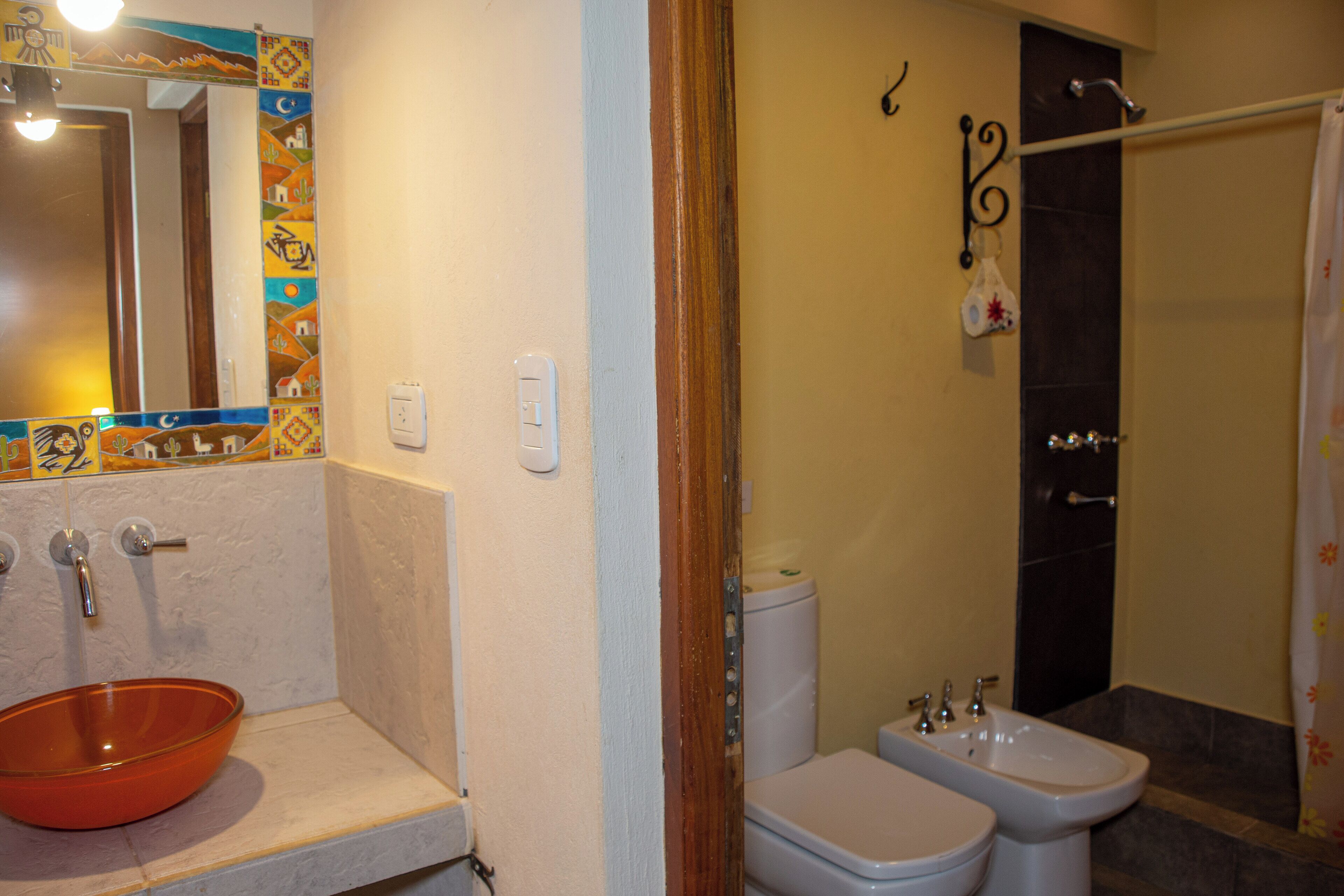 Un baño con lavamanos azulejado, inodoro y bidé.