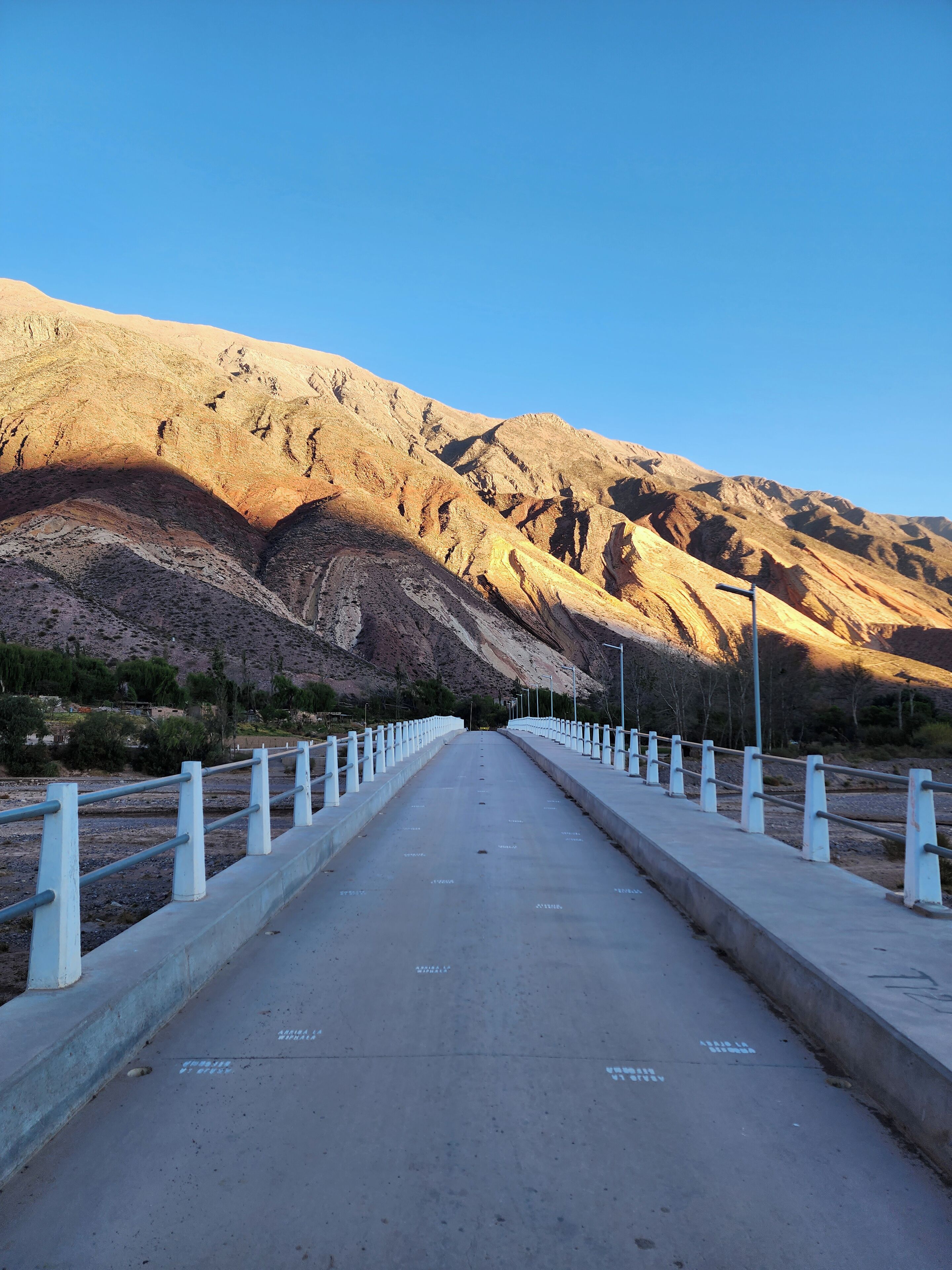 A concrete pathway with white railings leading towards a mountainous landscape.