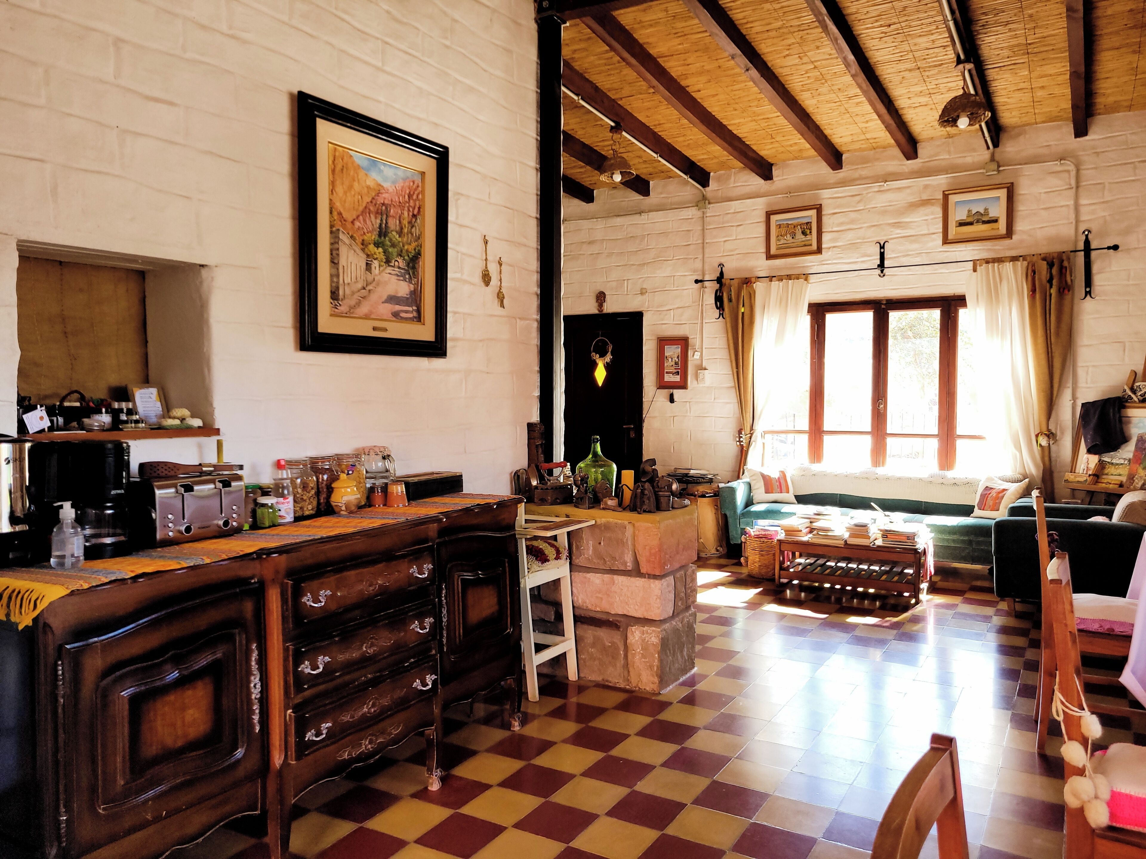 A rustic room with a checkered floor, wooden furniture, and a stone fireplace.
