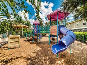 Explore the playground with a slide and climbing structure, surrounded by a deck and a fence.