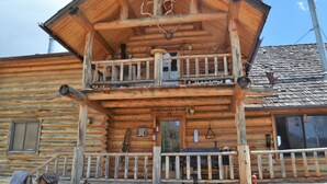 Een houten chalet met een balkon, een schoorsteen en een bord waarop staat 'HomeSweetHome'.