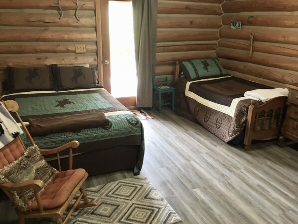 Une chambre située dans une cabane en rondins, avec un lit, une chaise et une petite table.