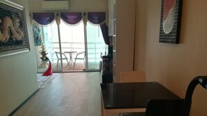 Una habitación con una mesa de comedor, sillas, un televisor y una ventana con cortinas.