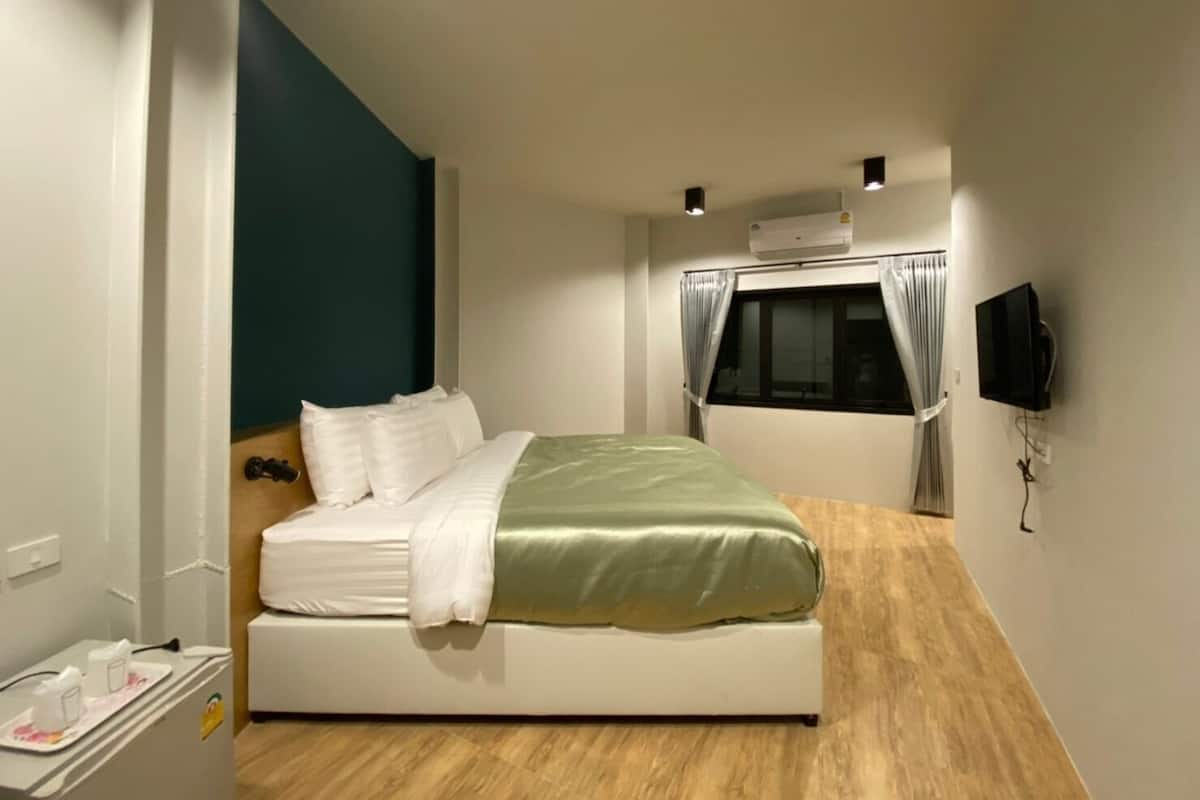 A modern hotel room with a bed, a TV mounted on the wall, and a window with curtains.