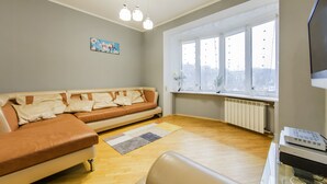 Ein Wohnzimmer mit Sofa, Teppich, Heizkörper und einem Fenster mit Ausblick.