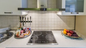 Eine moderne Küche mit Einbauherd, Spüle aus Edelstahl und einer Obstschale auf der Arbeitsfläche.