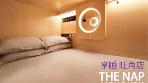 A hotel room with a bed, a circular light fixture on the wall, and a control panel. - The Nap Mong Kok (Kowloon)