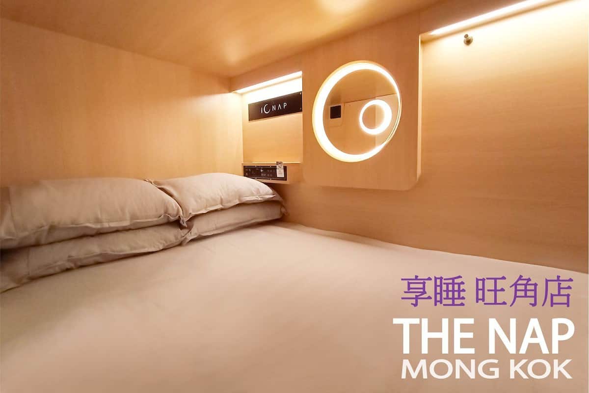 Ein Hotelzimmer mit einem Bett, einer runden Wandleuchte und einer Bedienkonsole.