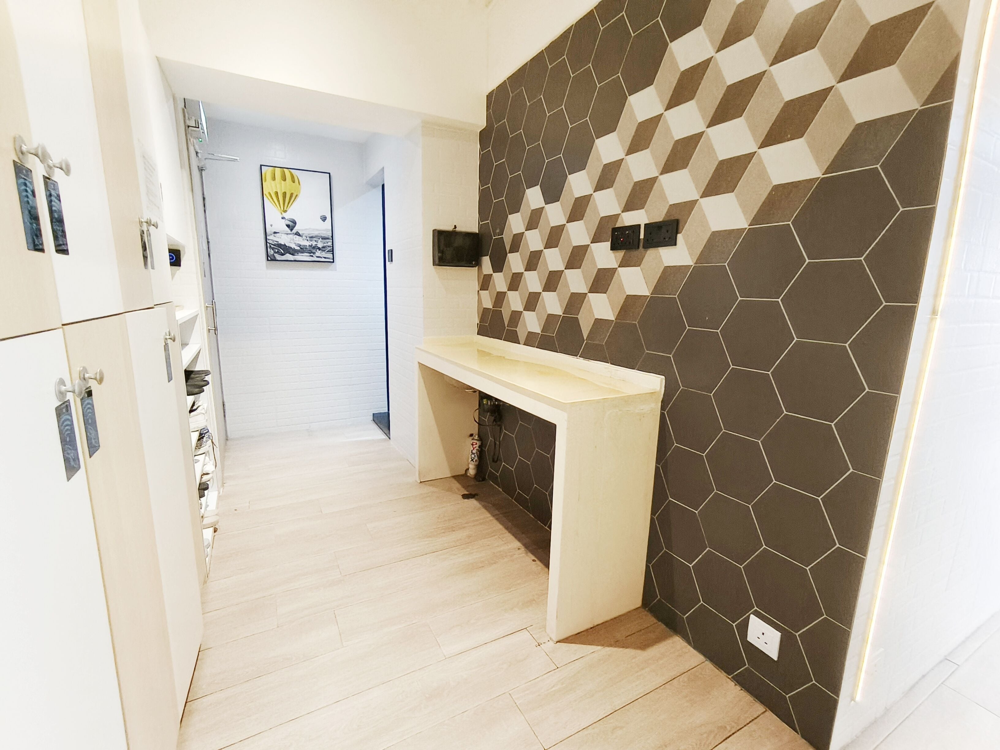 Una cocina moderna con salpicadero de azulejos hexagonales, encimera de madera y un armario blanco con horno integrado.