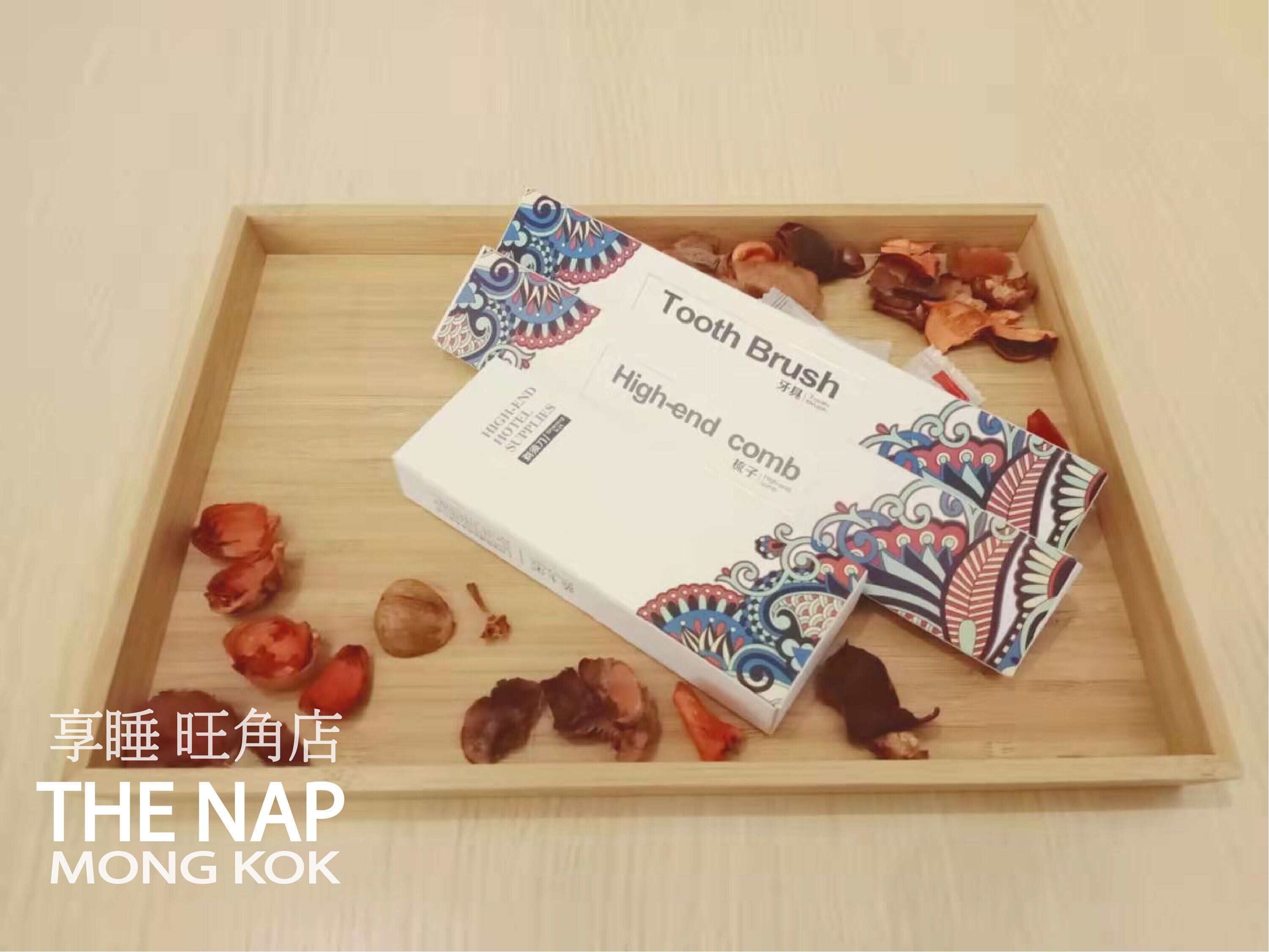 A wooden tray with a box of 'High-end comb' toothbrushes and some dried flowers.
