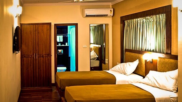 Een hotelkamer met twee bedden, een kledingkast, een airconditioner en een spiegel.