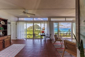 Enjoy ocean views from the balcony, featuring a wicker chair and potted plant.