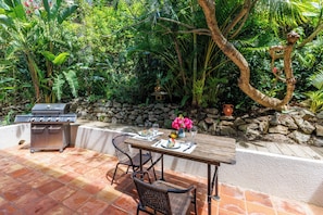 Enjoy al fresco dining on the patio surrounded by lush greenery and a stone wall.