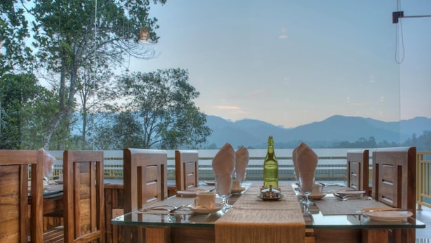 A dining table with chairs, a bottle, and plates set for a meal. - Indeevara Retreat (A unit of Saroma Hill Resorts) (Vythiri)