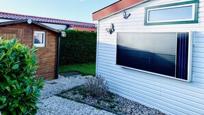Ein modernes Gebäude mit Garagentor, einer kleinen Gartenhütte und einem gepflegten Garten.