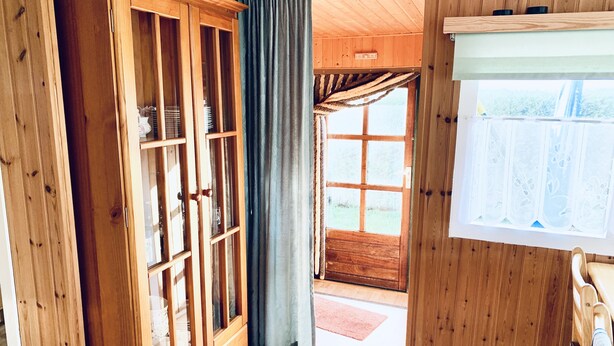 Ein Holzinnenraum mit einem Schrank, einem Vorhang und einem Fenster.