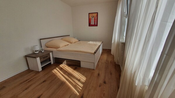 A bedroom with a bed, nightstand, and a painting on the wall.