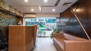 Un espace d’accueil avec un bureau en bois, un canapé en cuir et un mur décoré de mosaïques.