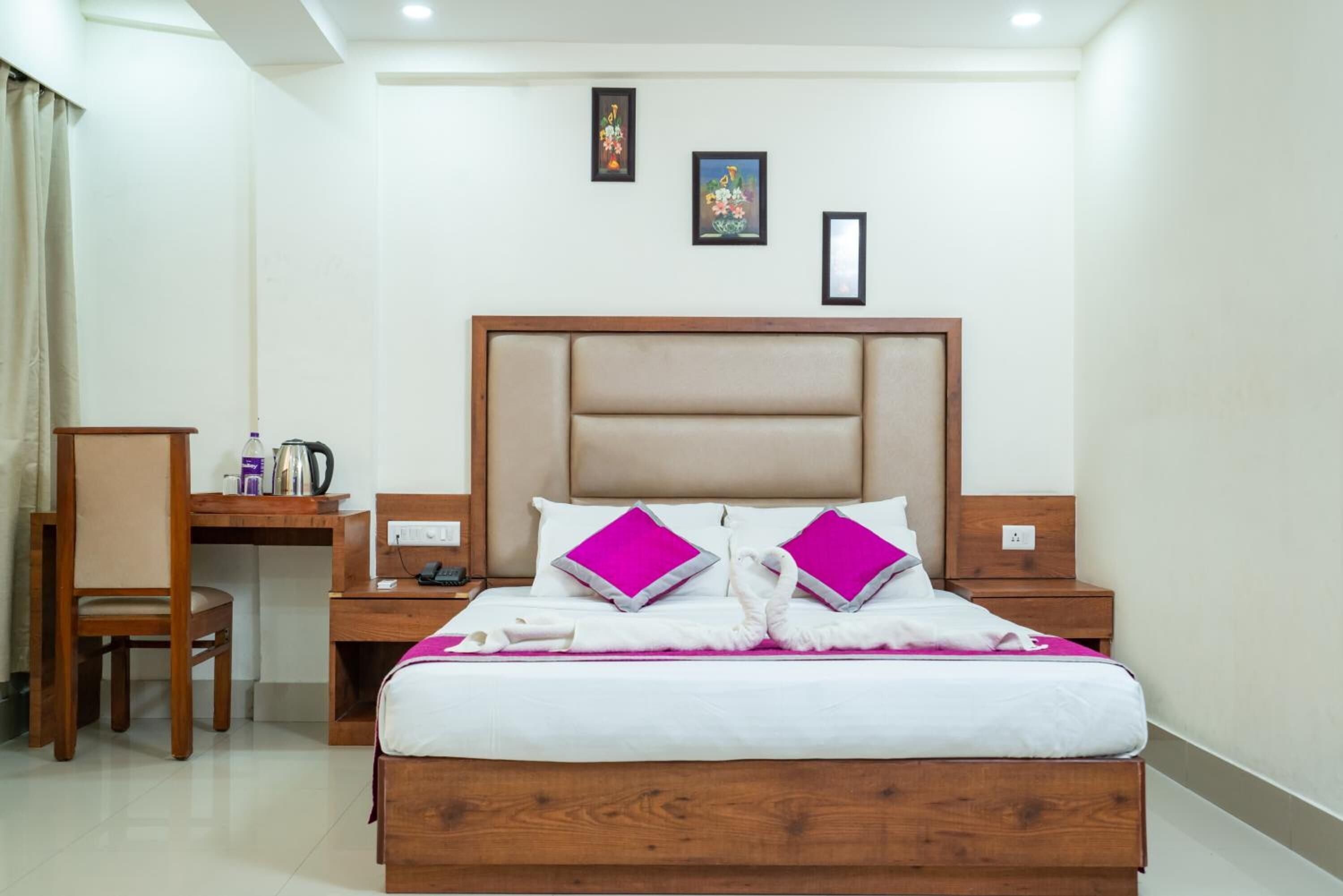 Een keurig opgemaakte hotelkamer met een houten bed, twee kussens, een bureau en een stoel.