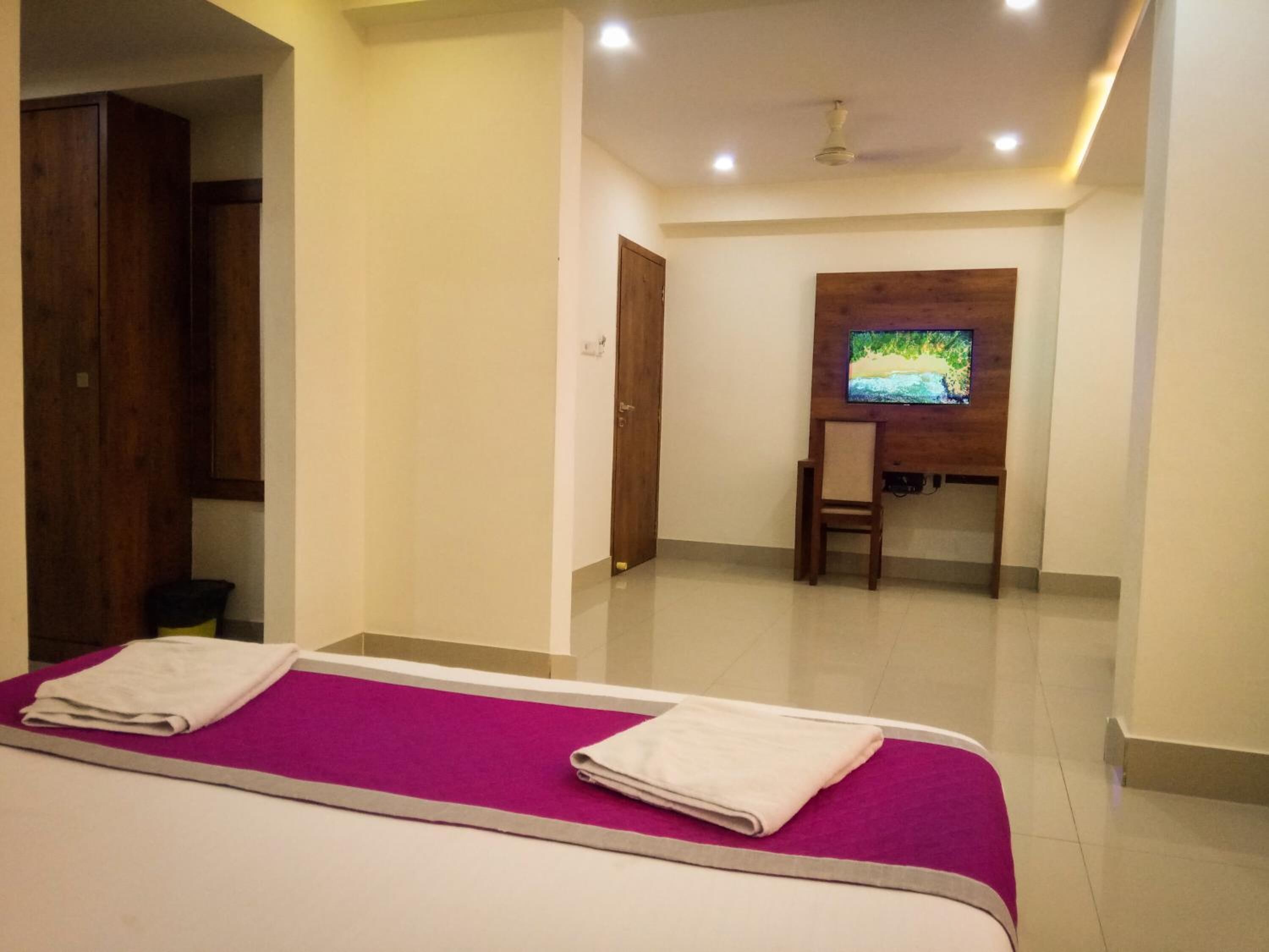 A hotel room with a bed, a desk, and a television.