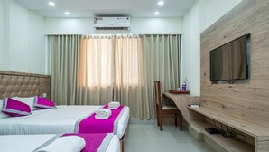 Une chambre d’hôtel avec deux lits, un téléviseur fixé au mur, un appareil de climatisation et un bureau avec une chaise.