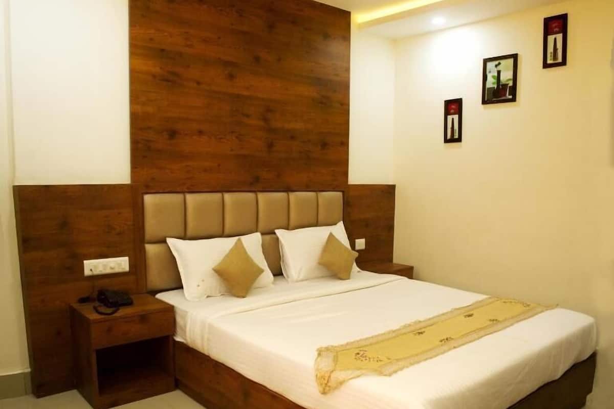 Ein Schlafzimmer mit einem Holzkopfende, einem Bett mit weißer Bettwäsche und einem Nachttisch mit einem Telefon.