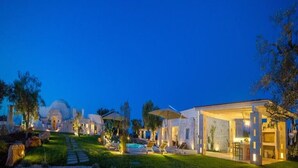 Un espacio exterior bien iluminado con piscina, sillas de descanso y un porche cubierto.