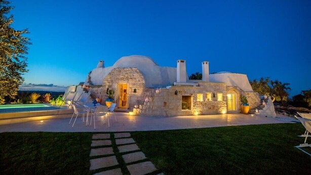 Una casa moderna con un diseño arquitectónico único, destacando un frente de piedra e ingreso bien iluminado.