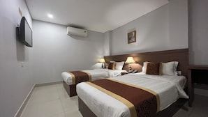 A hotel room with two beds, a flat-screen TV mounted on the wall, an air conditioner, and a painting on the wall. - GALAXY AIRPORT HOTEL (Ho Chi Minh City)