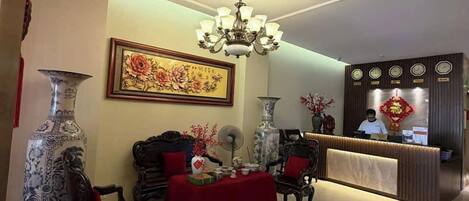 A spacious lobby with a chandelier, a reception desk, and traditional decor.