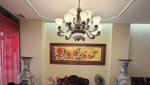 A traditional room with a chandelier, a red sofa, two chairs, a table with tea sets, and a large vase. - GALAXY AIRPORT HOTEL (Ho Chi Minh City)