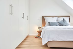 Une chambre à coucher avec un lit, une table de chevet, une lampe et des livres.